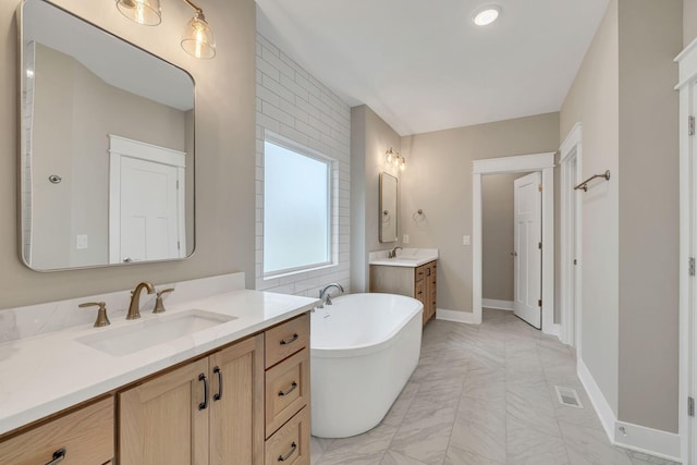 bathroom featuring a sink, a freestanding tub, baseboards, and two vanities