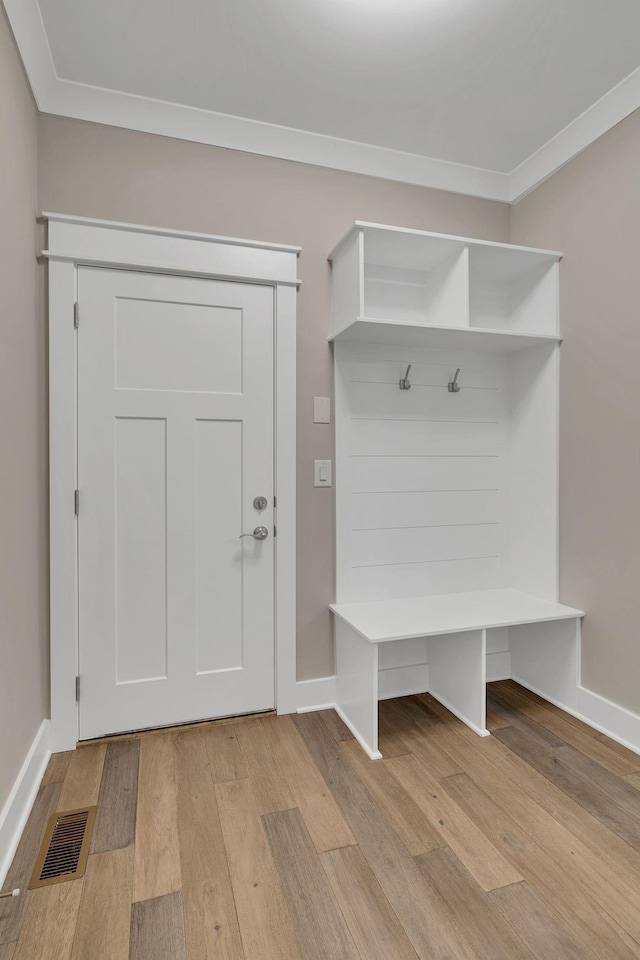 mudroom featuring visible vents, ornamental molding, light wood finished floors, and baseboards
