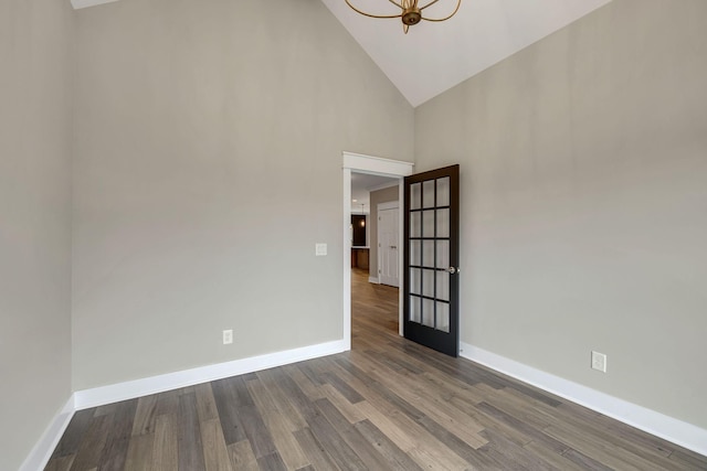 spare room with high vaulted ceiling, baseboards, a notable chandelier, and dark wood-type flooring