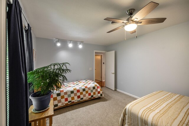 bedroom featuring a ceiling fan, visible vents, rail lighting, baseboards, and carpet flooring