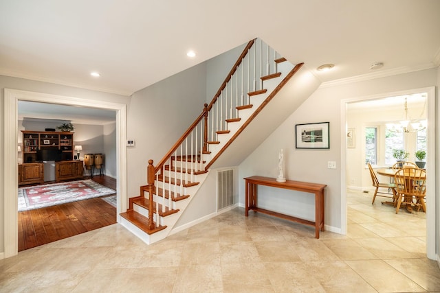staircase with crown molding, visible vents, baseboards, tile patterned floors, and a notable chandelier