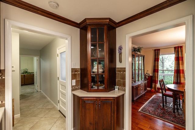 hallway featuring baseboards, ornamental molding, and light wood-style floors