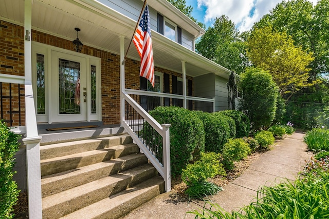 property entrance with a porch and brick siding