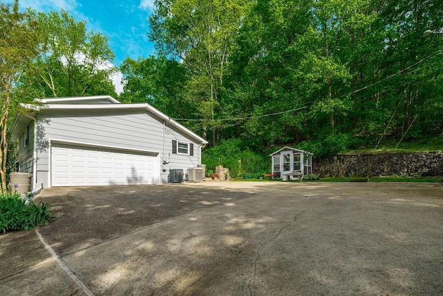 view of home's exterior featuring a garage, an outdoor structure, concrete driveway, and cooling unit