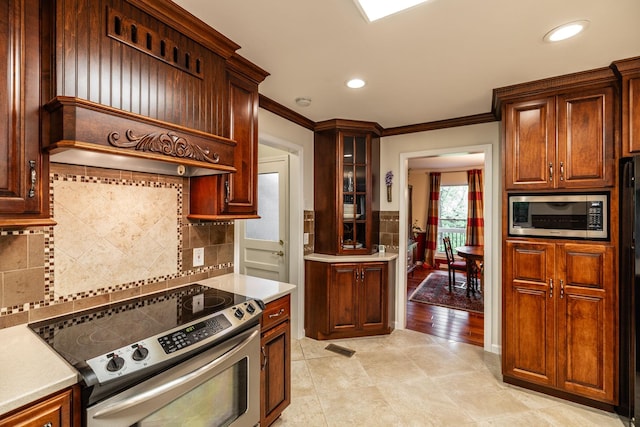 kitchen with crown molding, premium range hood, light countertops, tasteful backsplash, and appliances with stainless steel finishes