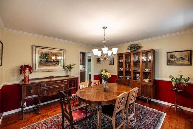 dining area featuring baseboards, a chandelier, ornamental molding, and wood finished floors