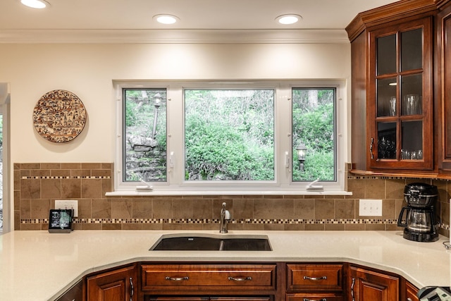 kitchen featuring a sink, glass insert cabinets, tasteful backsplash, and light countertops