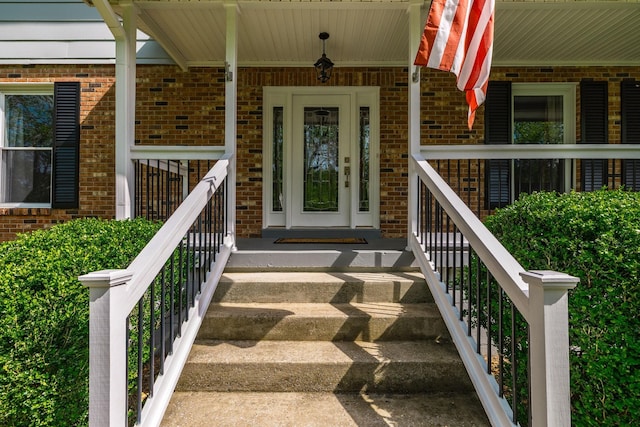 property entrance featuring a porch and brick siding