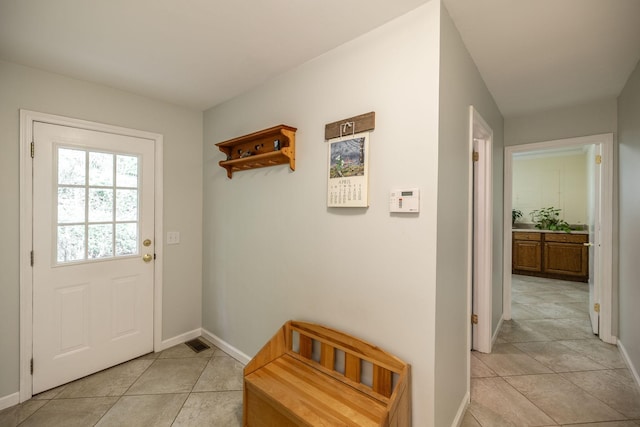 doorway featuring baseboards, visible vents, and light tile patterned floors
