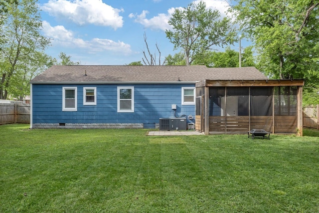 rear view of house with a fenced backyard, a lawn, and a sunroom