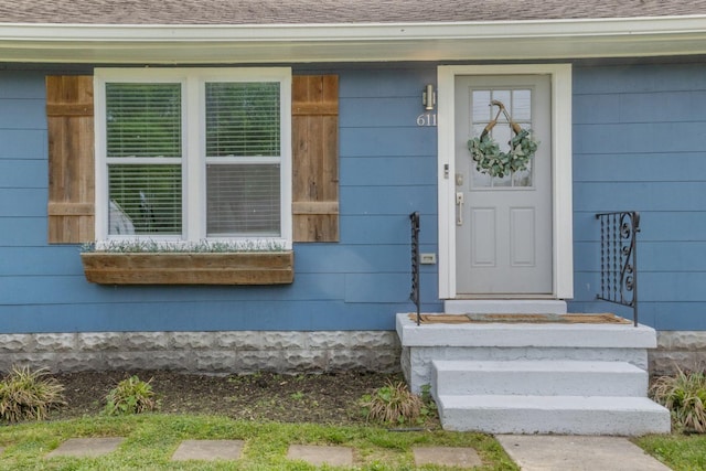 view of exterior entry with roof with shingles