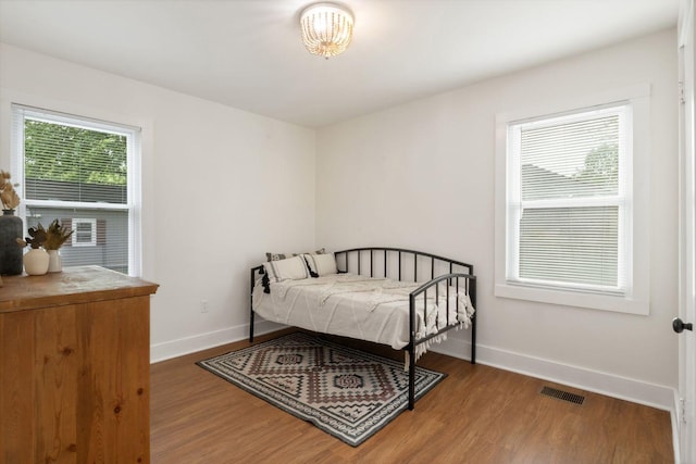 bedroom featuring baseboards, visible vents, and wood finished floors