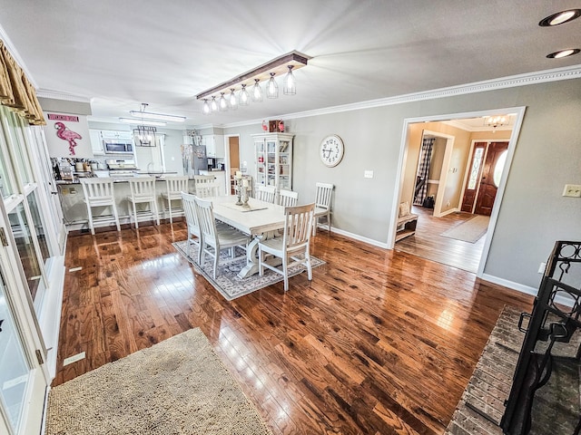 dining space with crown molding, baseboards, an inviting chandelier, and hardwood / wood-style floors