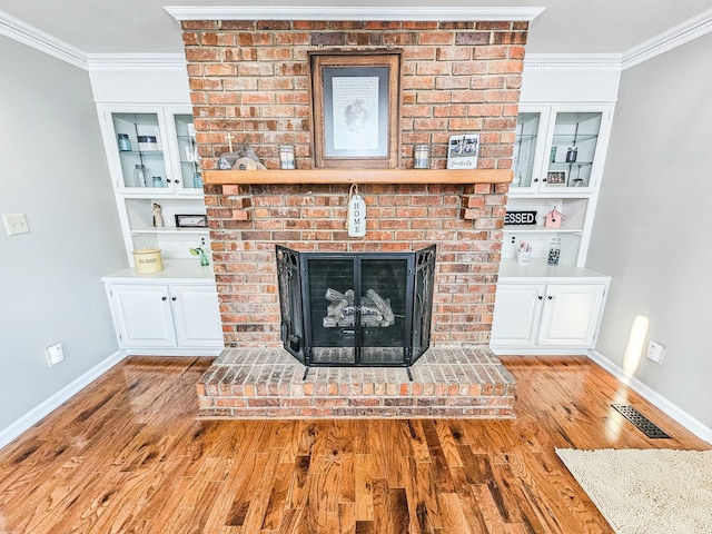living room featuring a brick fireplace, baseboards, ornamental molding, and wood finished floors