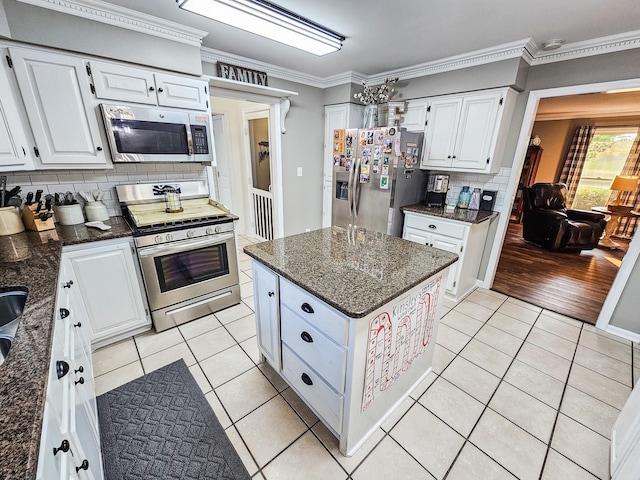 kitchen featuring decorative backsplash, white cabinets, dark stone countertops, appliances with stainless steel finishes, and light tile patterned floors