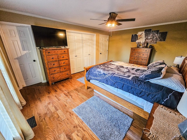 bedroom featuring crown molding, a ceiling fan, wood finished floors, and a closet