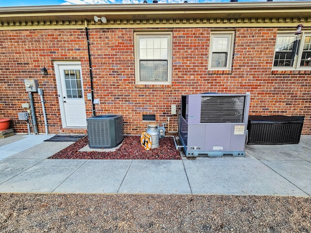 view of exterior entry with brick siding and central AC