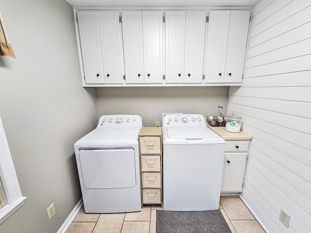 clothes washing area with cabinet space, separate washer and dryer, light tile patterned floors, and wooden walls