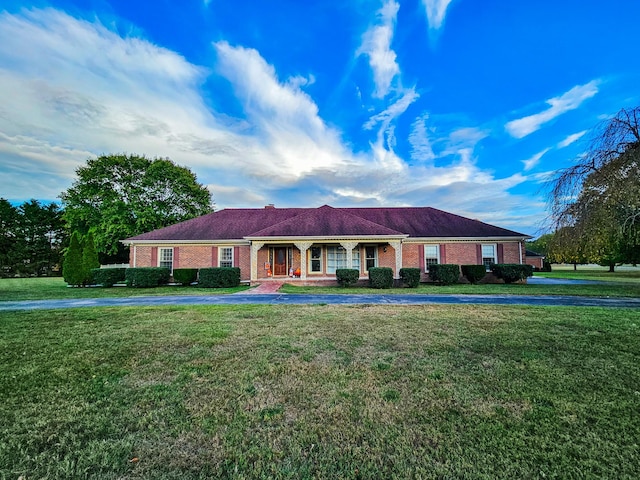 ranch-style house featuring a front yard, a porch, and brick siding