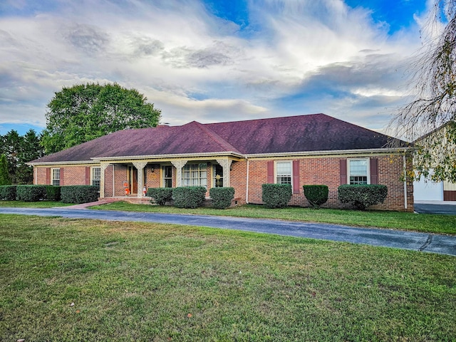 ranch-style house featuring a front yard, a porch, and brick siding