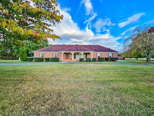 ranch-style home with brick siding, covered porch, and a front yard