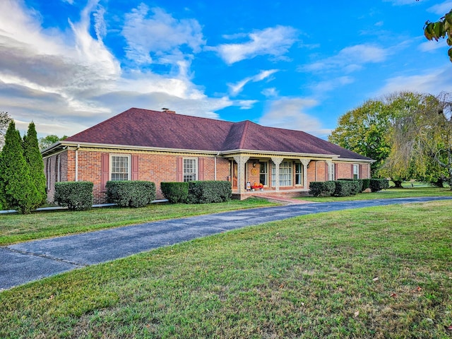 ranch-style house with a porch, brick siding, a front yard, and aphalt driveway