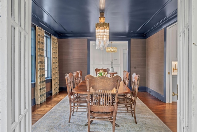 dining room featuring baseboards, ornamental molding, wood finished floors, and a chandelier