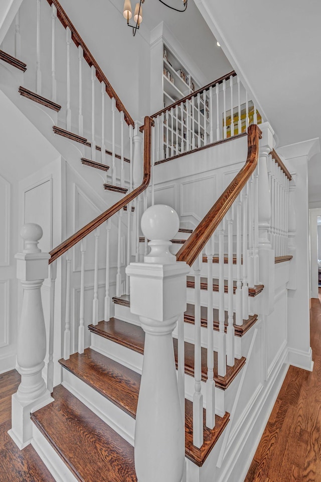 staircase featuring a decorative wall and wood finished floors