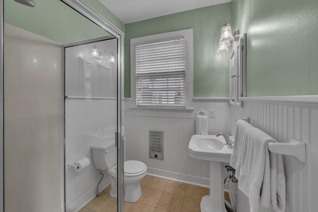 bathroom featuring wainscoting, a sink, toilet, tile patterned floors, and heating unit