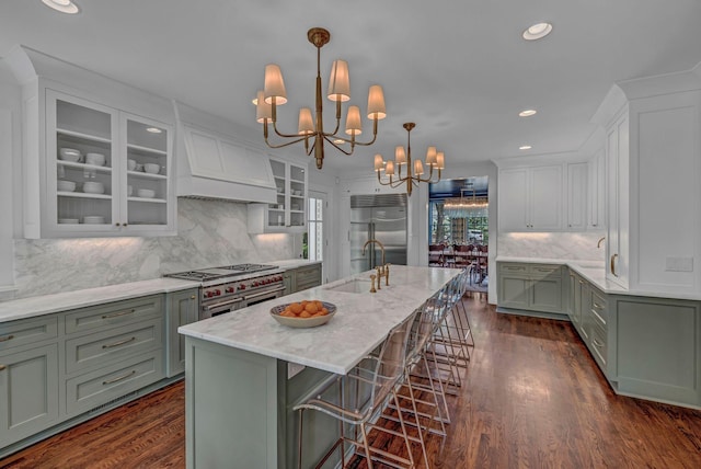 kitchen featuring a sink, a chandelier, custom range hood, premium appliances, and green cabinets