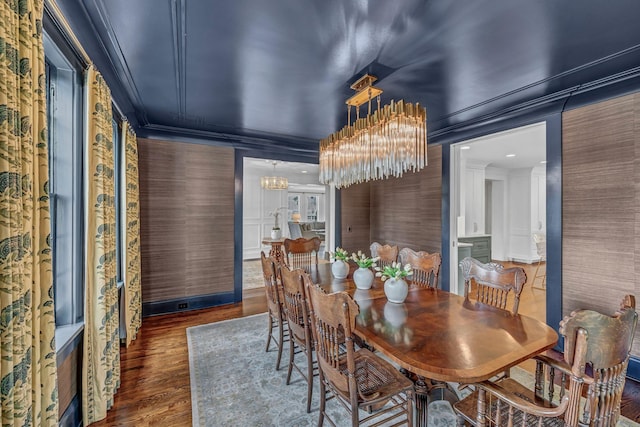 dining space with a notable chandelier, ornamental molding, and wood finished floors