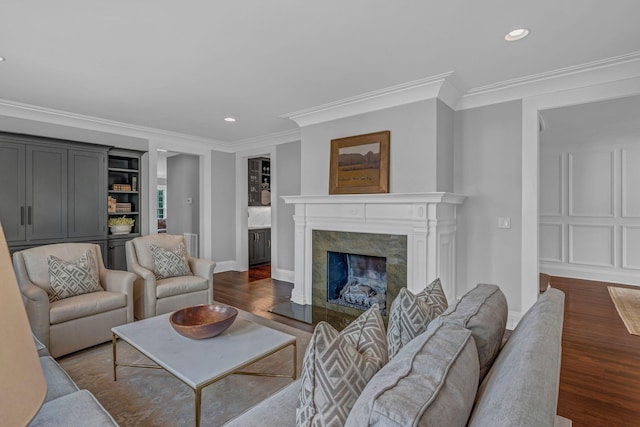 living area featuring crown molding, a premium fireplace, recessed lighting, and dark wood-type flooring