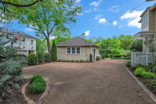 view of side of property featuring driveway and a shingled roof