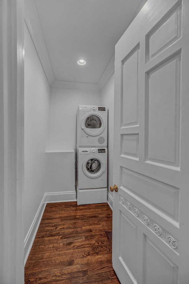 laundry area featuring laundry area, dark wood-style flooring, stacked washer and dryer, baseboards, and recessed lighting
