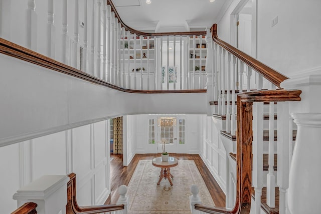stairs featuring ornamental molding, wood finished floors, a decorative wall, a high ceiling, and recessed lighting