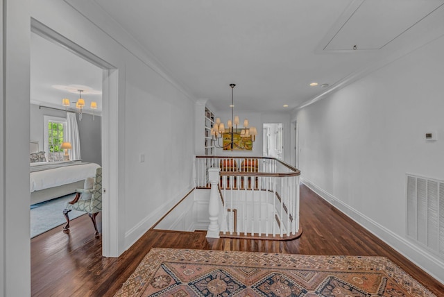 corridor with a chandelier, attic access, an upstairs landing, wood finished floors, and visible vents