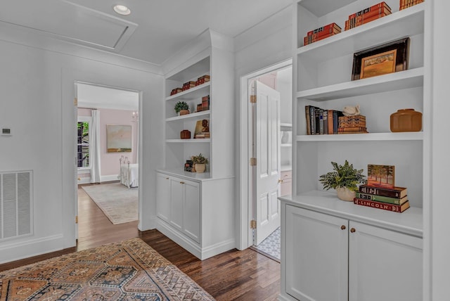 corridor with visible vents, attic access, dark wood finished floors, and built in features