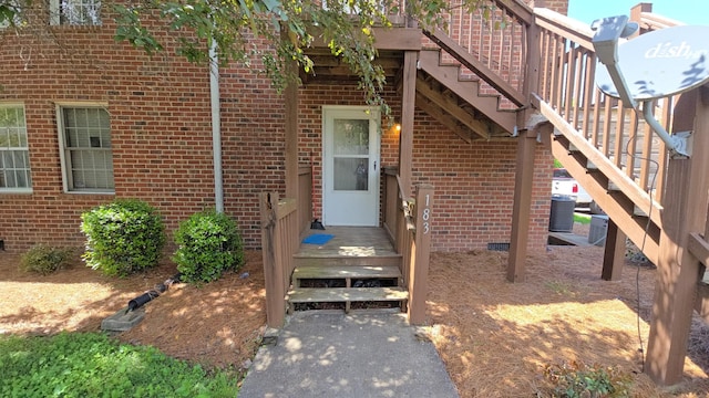 entrance to property featuring central air condition unit and brick siding
