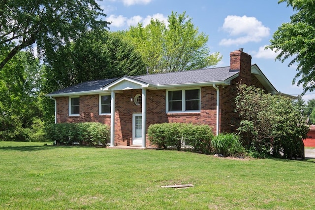 bi-level home with brick siding, a chimney, and a front lawn