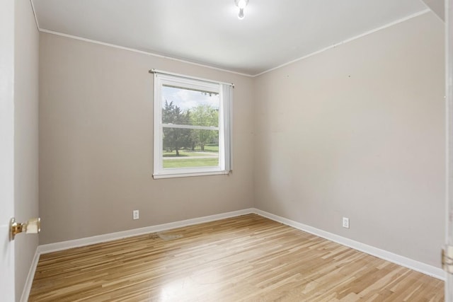empty room featuring light wood-style floors, ornamental molding, and baseboards