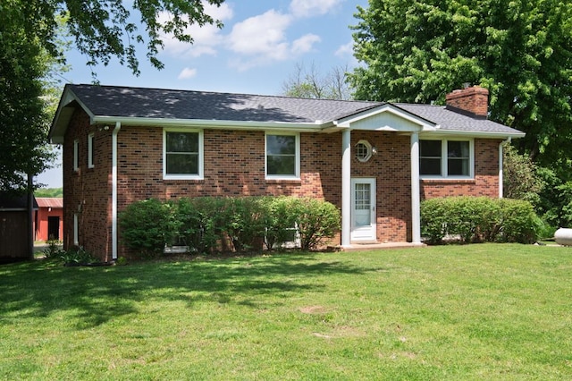 raised ranch with brick siding, a front yard, and a chimney