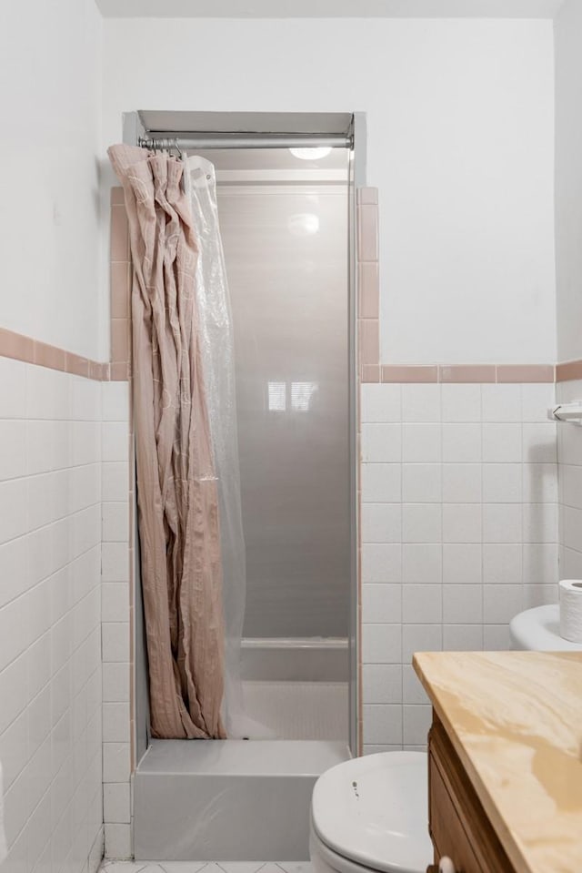 bathroom with tile walls, a stall shower, and toilet