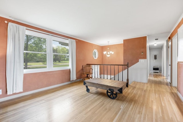 interior space featuring light wood-style floors, baseboards, an upstairs landing, and a notable chandelier