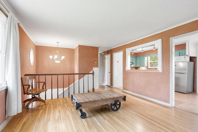 interior space with a chandelier, baseboards, an upstairs landing, light wood-type flooring, and ornamental molding