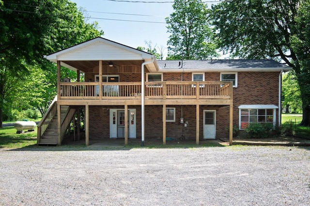 view of front of home with a ceiling fan, stairs, a deck, and brick siding
