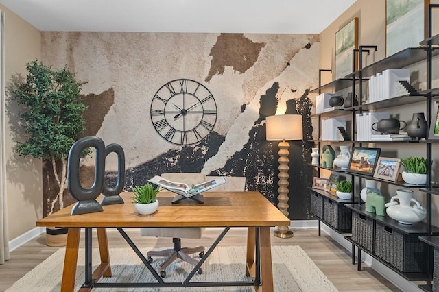 interior space with baseboards, an accent wall, and wood finished floors