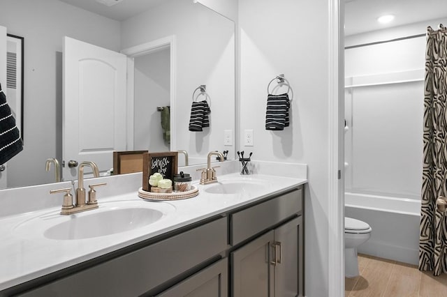 full bath featuring double vanity, a sink, shower / tub combo, and toilet
