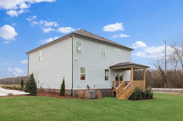 rear view of property featuring a lawn, stairway, a ceiling fan, and central AC unit