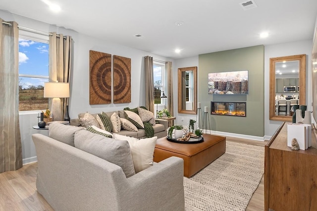 living room with visible vents, a healthy amount of sunlight, and light wood-style flooring