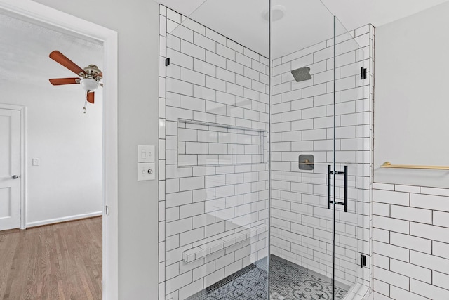 full bath featuring ceiling fan, a stall shower, and wood finished floors